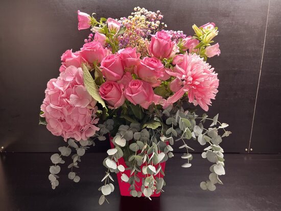 Pink vase with pink flowers in a cardboard bag